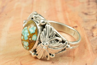Genuine Number 8 Turquoise set in Sterling Silver Ring. The Number 8 mine is located in Eureka County Nevada. Since 1976 there has been no Number 8 Turquoise mined. There is however, an existing stock pile that Mr. Dowell Ward, the last owner of the Number 8 mine, had stocked away for later sorting. The Turquoise is a collector's item--because once the reserve is gone there will be no more material released onto the market. The Gold Mining Company owns the claim to the Number 8 mine and it has been swallowed up by the gold mining operations. This is some of the last Number 8 Turquoise to be had and will be a great addition to your collection. Created by Navajo Artist Bobby Piaso. Signed by the artist.